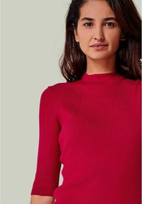Strickpullover in Rot, figurbetont mit ribbeliger Textur und kurzen Ärmeln, ausgestattet mit einem runden Ausschnitt und dezenten vertikalen Nähten.
