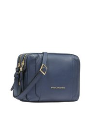 Navyblaue Leder-Umhängetasche mit goldfarbenen Beschlägen, zwei Reißverschlussfächern und abnehmbarem Riemen. Glatte Textur mit dezenten Steppnähten.