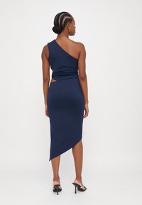 Robe asymétrique navy en tissu lisse, avec un design à une épaule, un détail torsadé à la taille et un ourlet angulé élégant.