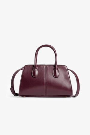 Bolso burdeos de cuero suave, con dos asas redondeadas, una correa para el hombro y detalles minimalistas cosidos.