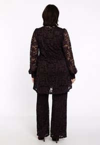 Lace tweedelige set in donkerpaars bestaat uit een tuniek met lange mouwen en een bloemenpatroon, en wijde broekspijpen, beide met golfranden.