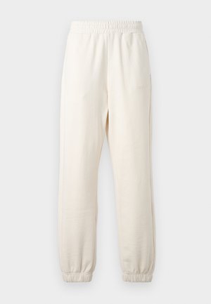 Pantalones de sudadera color crema hechos de tela suave, con cintura elástica y puños acanalados. Detalle del logo en el costado.