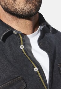 Jeanshemd mit dunkler Waschung, ausgestattet mit weißen Knöpfen und kontrastierenden gelben Nähten entlang der Knopfleiste. Der Kragen ist spitz und es gibt eine Tasche.