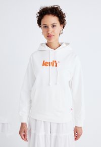 Vit hoodie med känguruficka, har en orange "Levi's"-logotyp. Har en dragkedjehuva och ribbade ärmslut. Enkel design, mjuk textur.
