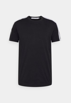 T-shirt noir à manches courtes avec col rond, rayures blanches et texte de la marque le long des épaules et des manches.