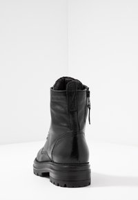 Stivale alla caviglia in pelle nera con finitura texturizzata, chiusura con zip sul lato e suola in gomma robusta con design del battistrada rettificato.