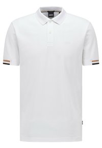 Polo blanc en tissu doux, avec un col, une patte de boutonnage à deux boutons et des poignets rayés marron, noir et blanc. Détails de logo subtils.