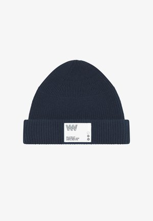 Marine gebreide beanie met een geribbelde textuur, met een omgeslagen rand en een wit label met het merklogo en verzorgingsinstructies.