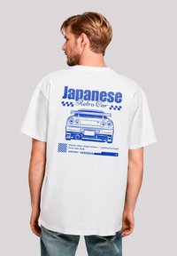 White oversized t-shirt featuring a blue graphic of a retro car on the back with text reading "Japanese Retro Car" and decorative stripes.