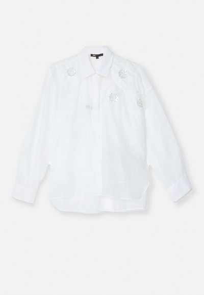 Chemise blanche en tissu léger, ornée de broderies florales et de sequins sur le devant supérieur, avec un col classique et des manches longues.
