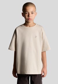 Beige bomulds T-shirt med en afslappet pasform, rund hals og korte ærmer, der har et lille broderet logo på brystet.