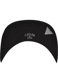 Sort kasket med en forlænget skygge, der har teksten "CAYLER & SONS" i hvid. Inkluderer en trekantet sølvaccent på siden.