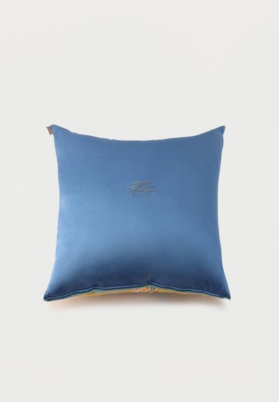 Coussin carré bleu avec un subtil emblème brodé de cheval ailé centré sur le devant, fond uni, bord visible à motif jaune.