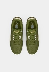 Ζευγάρι πράσινων αθλητικών παπουτσιών Puma με λευκές λεπτομέρειες και κορδόνια, σε θέαση από πάνω σε απλό λευκό φόντο.