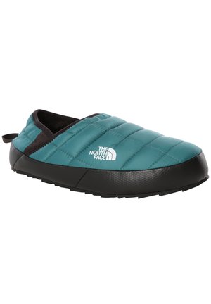 Turkusowe ocieplane buty wsuwane z czarną podeszwą i wykończeniem, pikowana cholewka oraz białe logo The North Face po boku.