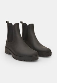 Cizme Chelsea din cauciuc negru, cu panouri elastice pe lateral, sole texturate din cauciuc, vârfuri rotunjite și mânere la spate pentru o purtare ușoară.