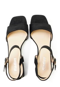 Zwarte suède sandalen met een vierkante neus, enkelband en een kleine goudkleurige gesp. Zachte, gladde textuur met een beige binnenzool.