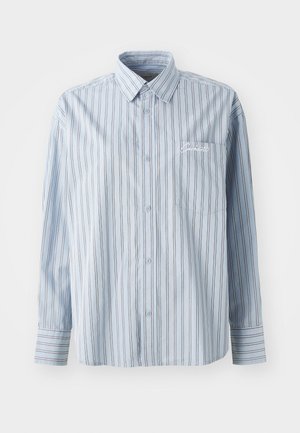 Lys blå langermet skjorte med knapper og hvite og mørke vertikale striper, samt en brystlomme med hvit skrifttypebrodering.