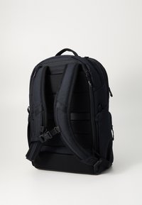 Sac à dos noir avec des bretelles rembourrées, des zips, des poches latérales et un tissu texturé. Comprend des bretelles réglables pour un ajustement et une stabilité optimale.