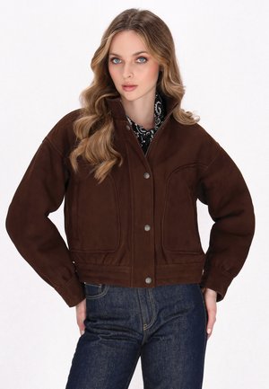 Giacca in suede marrone con colletto alto, chiusura anteriore con bottoni a pressione e tasche laterali, caratterizzata da un design cropped e una superficie testurizzata.
