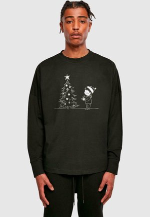 Sort langærmet sweatshirt med en hvid illustration af et barn ved et juletræ, som er pyntet med pynt og har en stjerne på toppen.