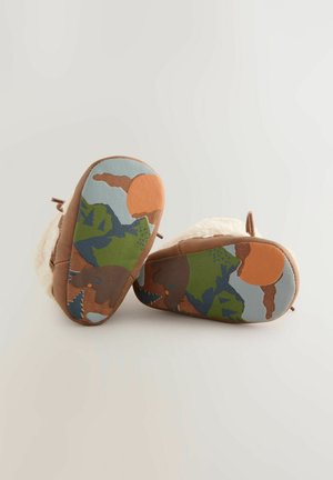 Braune Wildleder-Stiefeletten mit einem flauschigen weißen Innenfutter, ausgestattet mit einer mehrfarbigen Camouflage-Sohle in Blau-, Grün-, Orange- und Brauntönen.