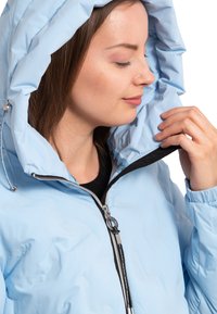 Helle blaue Kapuzenjacke mit glatter Textur, ausgestattet mit einem Reißverschluss, schwarzen Akzenten und einer Kordelzugdetails in der Nähe der Kapuze.
