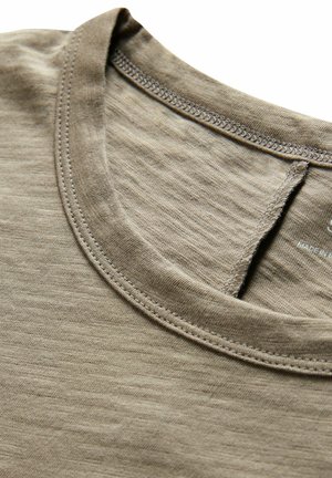 Hellbraunes Baumwoll-T-Shirt mit rundem Ausschnitt, feiner Textur und kontrastierenden Nähten entlang des Kragens und der Schulternaht.