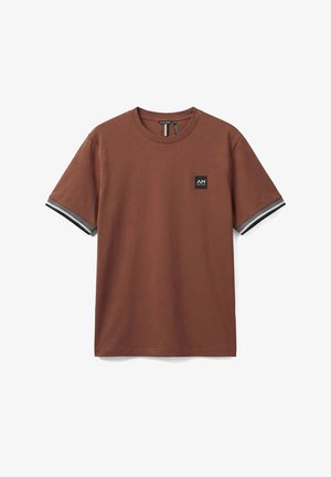 Camiseta marrón de manga corta con puños a rayas en negro, blanco y gris, y un pequeño parche con el logo "AM" en negro en el pecho izquierdo.