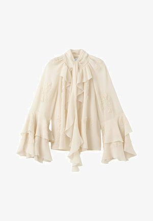 Kremasta bluza s volanom na visokom ovratniku i mašnom, slojevitim rukavima u obliku zvona te suptilnim cvjetnim vezom na tkanini.