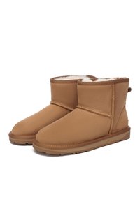 Tan suede ankle boots with a soft white fur lining, rounded toe, and stitched detailing. Low-profile rubber sole for traction.