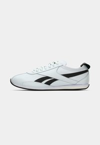 Pantofi sport albi, cu partea de sus joasă, cu dungi negre pe laterale, șireturi albe și un tab de prindere negru la călcâi, prezentati în profilul lateral drept pe un fundal deschis.