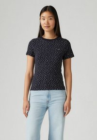 Marineblaues Polka-Dot-T-Shirt aus Baumwolle mit Rundhalsausschnitt und kurzen Ärmeln, kombiniert mit hellblauen gerade geschnittenen Jeans.