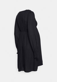Vestido negro de manga larga hecho de una tela ligera, con cintura fruncida y corte holgado, puños elásticos y un escote trasero modesto.