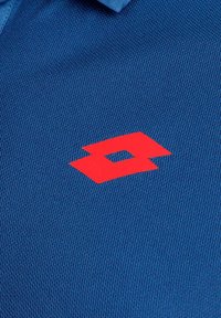 Camisa polo azul con una tela texturizada. Cuenta con un prominente logo rojo que se asemeja a un doble diamante.