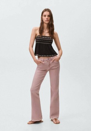 Black strapless top with geometric embroidery, paired with light pink flared jeans, highlighting a relaxed fit and casual style.