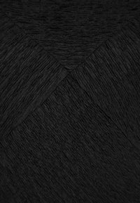Tissu noir avec un motif texturé côtelé disposé en sections diagonales superposées formant un motif chevron subtil.