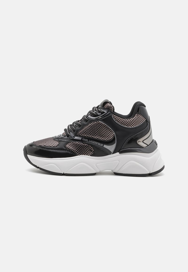 Black and silver sneaker featuring mesh and leather materials, rounded toe, thick white sole, and black accents along the sides.