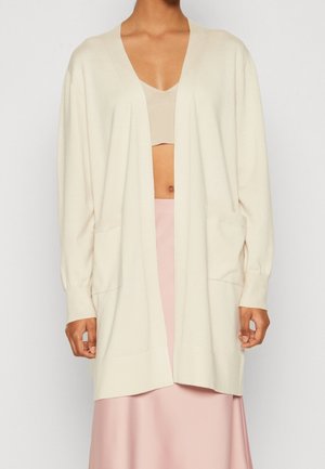 Cardigan color crema realizzato in tessuto morbido; presenta un collo a V, maniche lunghe, due tasche frontali e una vestibilità morbida.
