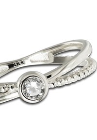 Bague en argent avec des anneaux entrelacés, ornée d'une pierre précieuse ronde et claire au centre et de petits accents clairs le long d'un anneau. Détail de surface texturée.