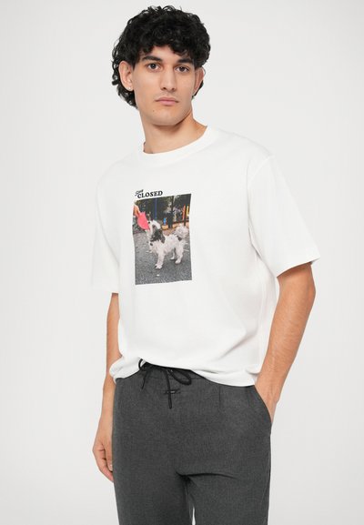 T-shirt branca de algodão com uma impressão fotográfica de um cão a brincar com um brinquedo, apresentando texto preto que diz "Desculpe, FECHADO."