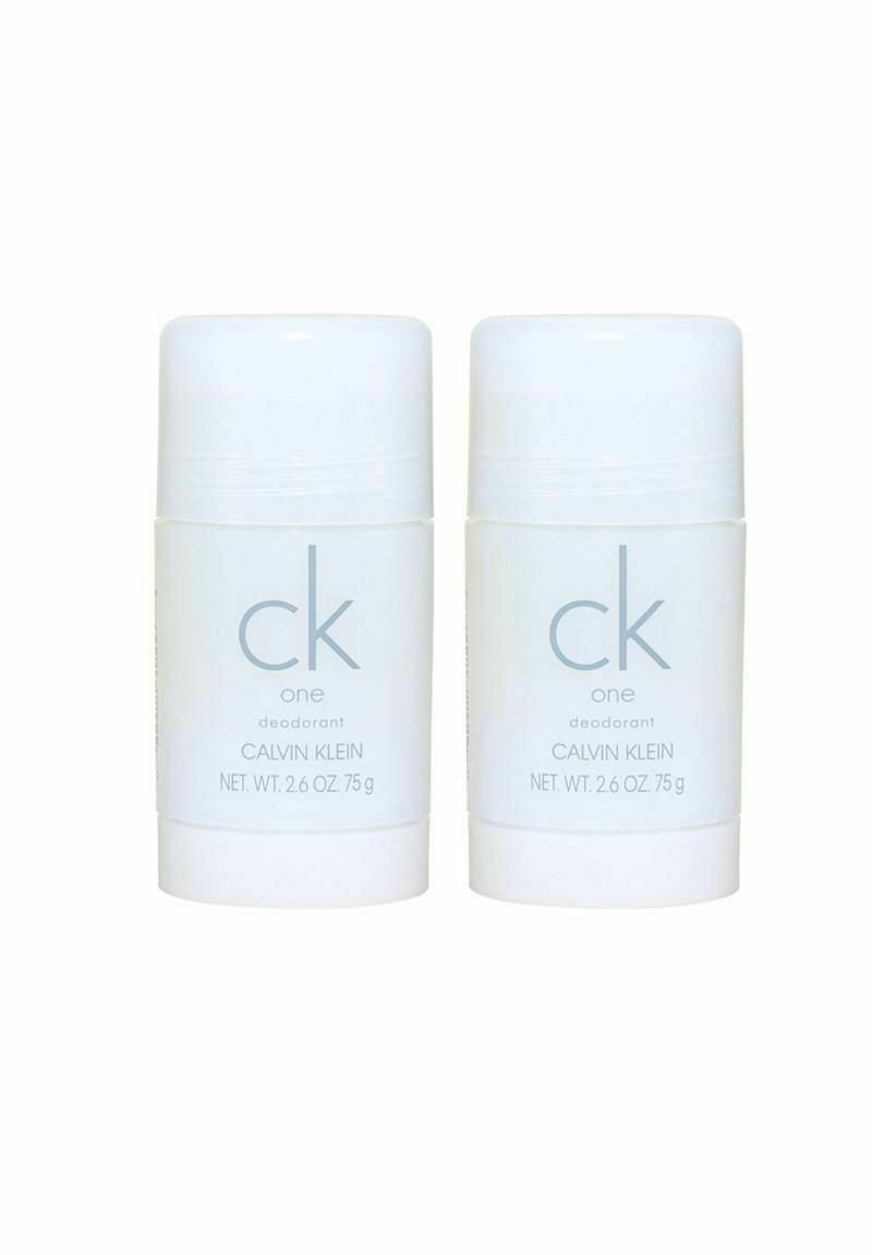 Två vita deodorantstift med cylindrisk form, med ljusgrå text "ck one deodorant Calvin Klein," 75 g vardera. Slät yta.
