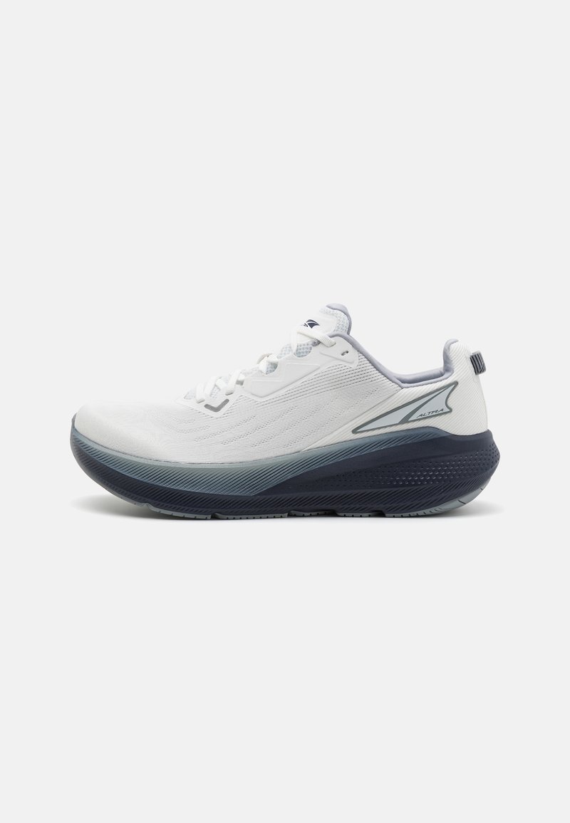 White athletic shoe with a textured upper, navy accents, a rounded toe, and a thick sole for cushioning. Features lace closure and reinforced heel.
