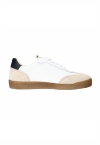 Baskets basses en cuir blanc avec un capuchon en suède beige, un accent de talon noir et une semelle en caoutchouc brun texturé. Présente une couture ton sur ton et des lacets plats.