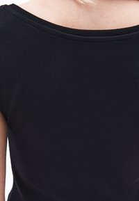 Maglietta nera a costine con un ampio scollo arrotondato e maniche corte, caratterizzata da un tessuto liscio e testurizzato con una forma aderente.