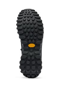 Musta kumipohja, jossa on karheaa kuviointia, johon on lisätty pyöreitä ja suorakulmaisia nystyröitä, kirkkaan keltaisella Vibram-logolla korostettuna.