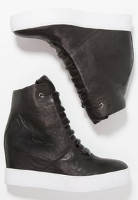 Černé kožené wedge tenisky s hladkou texturou, vybavené bílou podrážkou a shromážděným designem po stranách. Součástí je detail designu šněrování.