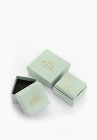 Mint green jewelry boxes with a matte finish, featuring gold lettering. One box is open showing a black interior. Simple geometric design.