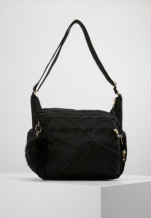Sac bandoulière noir avec plusieurs compartiments zippés, un motif texturé, des ferrures dorées, une sangle ajustable et un porte-clés noir pelucheux en accessoire.