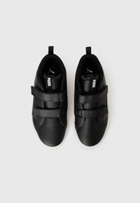 Chaussures en cuir noir avec deux sangles Velcro, bout arrondi et semelle en caoutchouc blanc. Logo PUMA affiché sur la languette et sur le côté.
